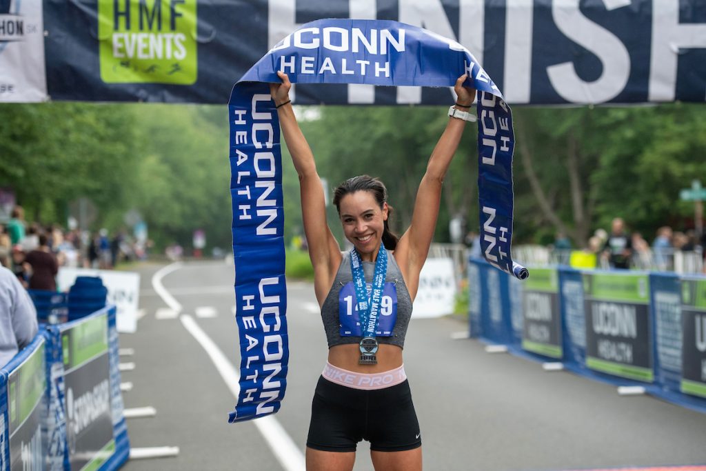 Woman holding up finish line tape at the UConn Health Half Marathon   runner, marathoner, race, marathon, simsbury 