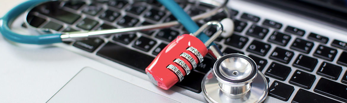 Combination lock and stethoscope laying on top of a laptop computer