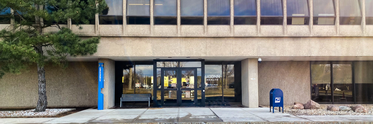 Building entrance with road in front, tree on the left mailbox on the right
