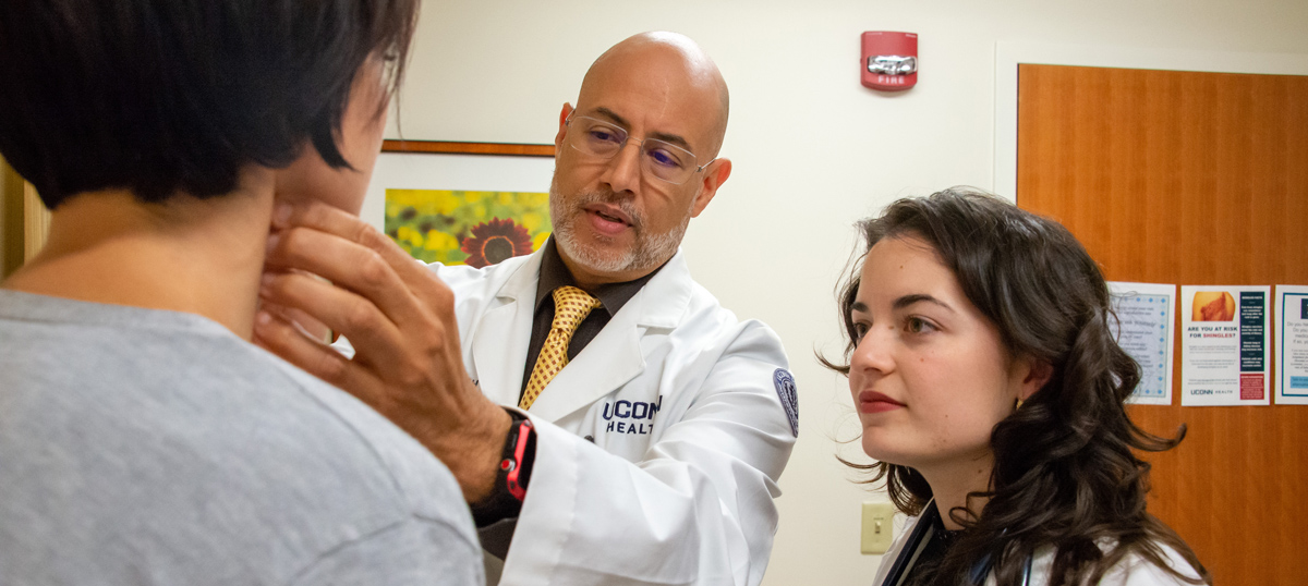 Doctor checking patient throat with a student observer