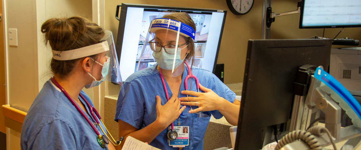 Nursing student with face coverings and masks in front of a computer talking