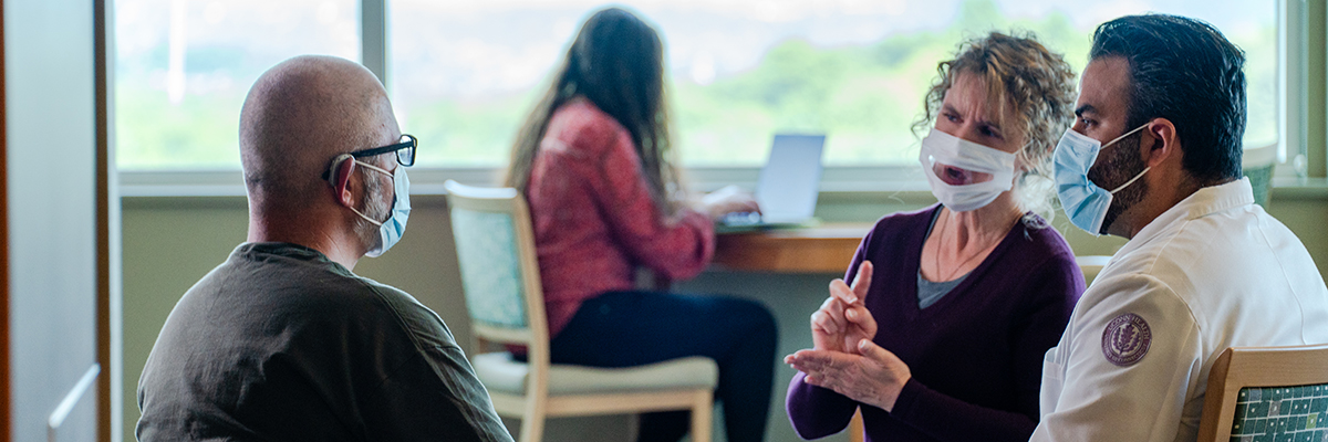 An interpreter signing to a patient with a provider sitting nearby